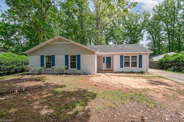 ranch-style house with roof with shingles and fence