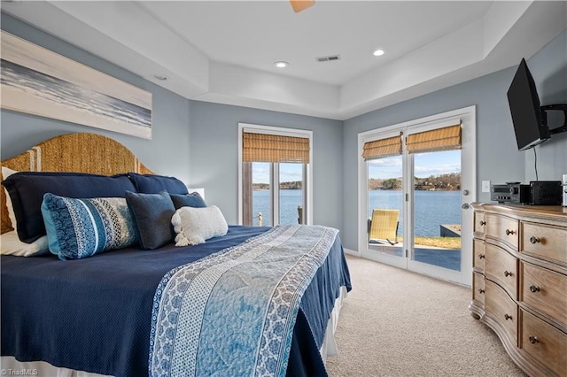 bedroom featuring light colored carpet, a raised ceiling, and access to outside