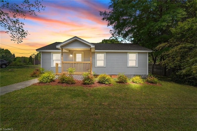 view of front of home with a porch, fence, and a front lawn