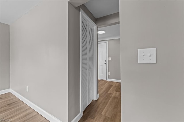 corridor with baseboards and wood finished floors