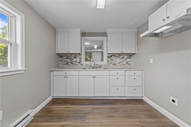 kitchen featuring white cabinets, a sink, light countertops, backsplash, and under cabinet range hood