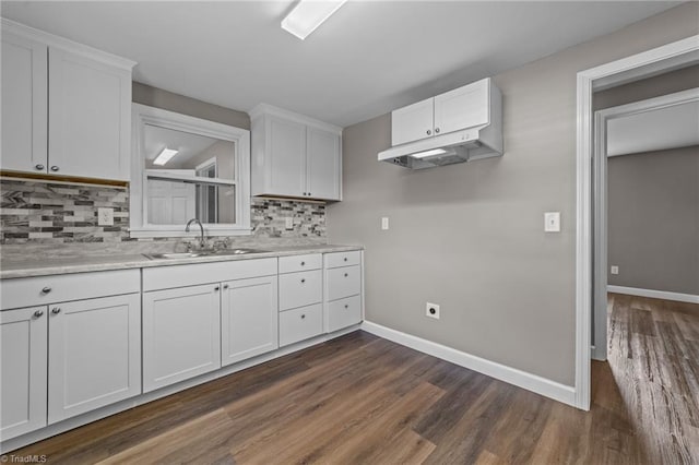 kitchen with baseboards, dark wood-type flooring, white cabinets, tasteful backsplash, and a sink