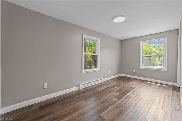 empty room featuring wood finished floors, baseboards, and a baseboard heating unit