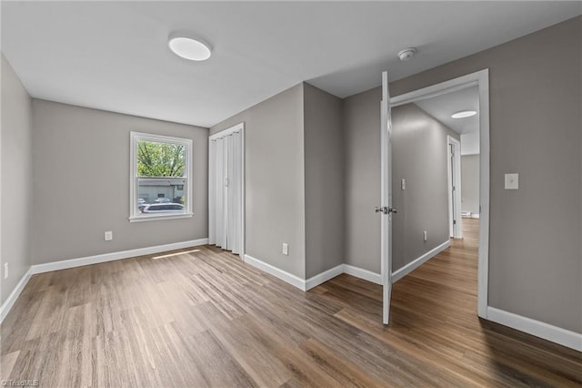 unfurnished bedroom featuring baseboards, a closet, and wood finished floors
