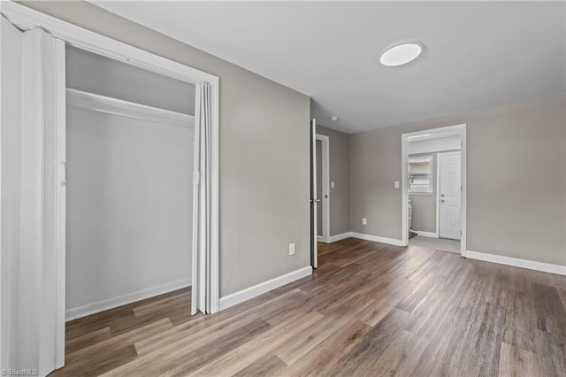 unfurnished bedroom with baseboards, wood finished floors, and a closet