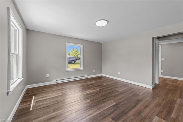 spare room with plenty of natural light, baseboards, dark wood-type flooring, and baseboard heating