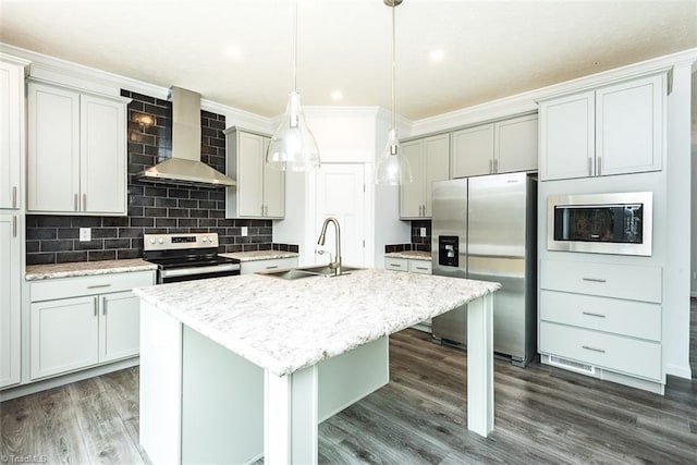 kitchen with wall chimney range hood, crown molding, a sink, a kitchen island with sink, and appliances with stainless steel finishes