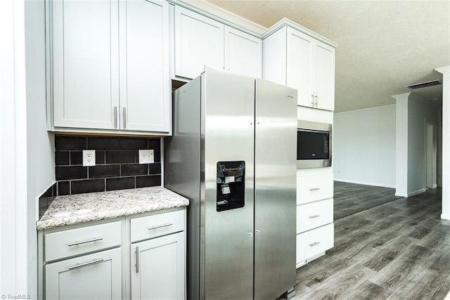 kitchen featuring stainless steel appliances, visible vents, decorative backsplash, wood finished floors, and light stone countertops