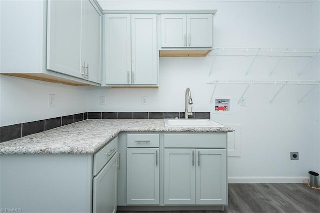 kitchen with baseboards, a sink, dark wood-type flooring, and light countertops