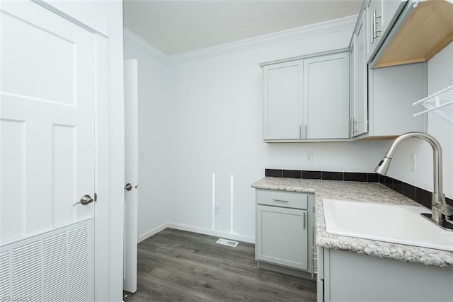 laundry room featuring visible vents, crown molding, dark wood-style flooring, and a sink