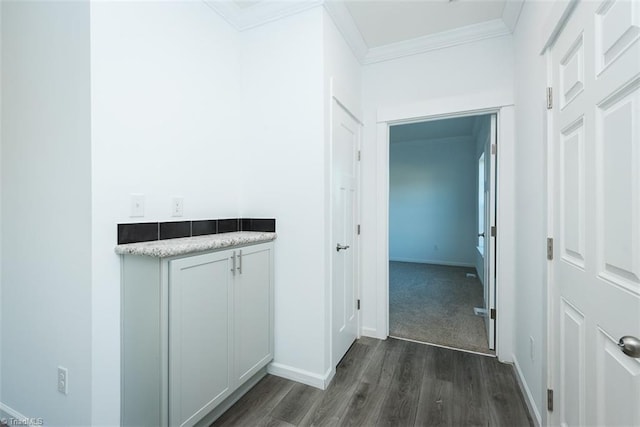hall with crown molding, baseboards, and dark wood-style flooring