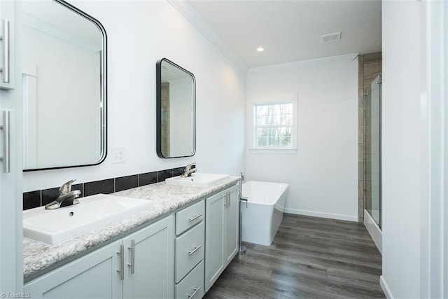 full bathroom with a freestanding tub, a stall shower, ornamental molding, and a sink
