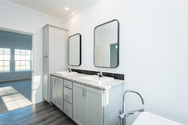 full bathroom featuring double vanity, wood finished floors, crown molding, and a sink