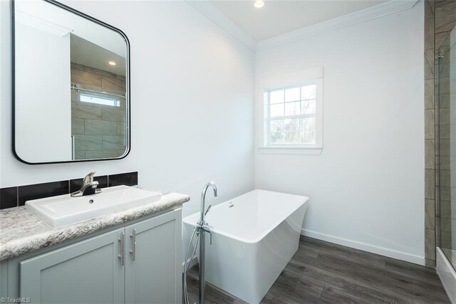 bathroom featuring tiled shower, wood finished floors, a freestanding tub, vanity, and ornamental molding
