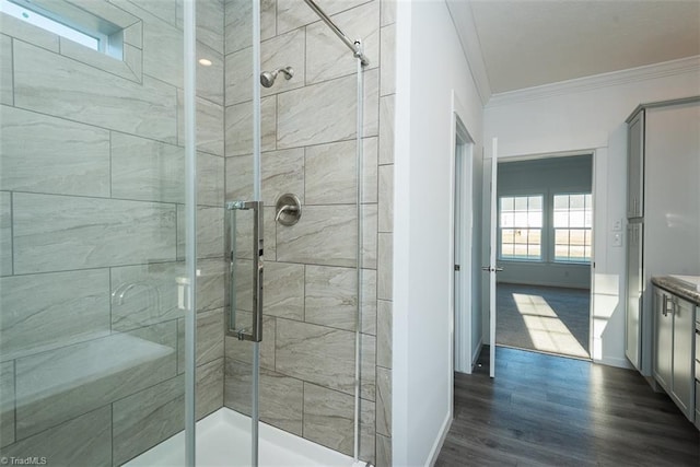 full bath with baseboards, wood finished floors, ornamental molding, and a stall shower