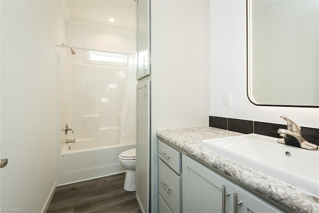bathroom with washtub / shower combination, wood finished floors, toilet, vanity, and ornamental molding