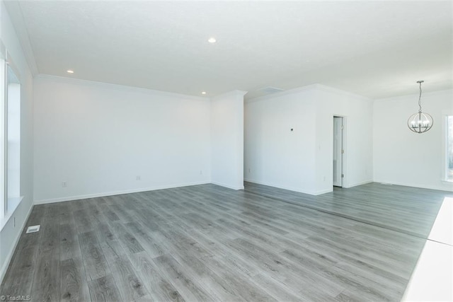 unfurnished living room featuring visible vents, an inviting chandelier, recessed lighting, wood finished floors, and ornamental molding