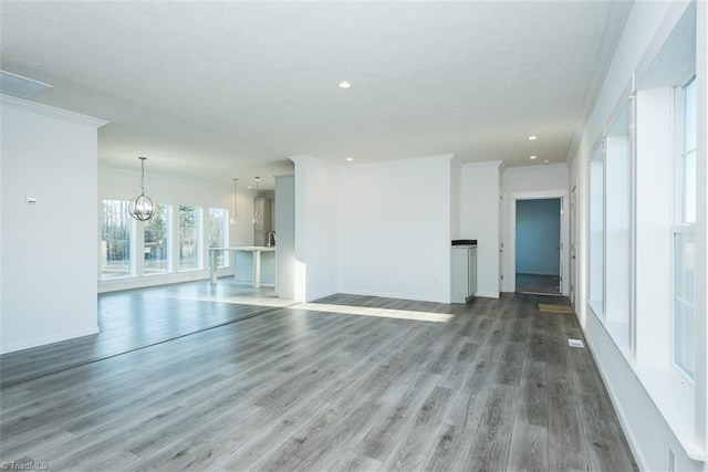 unfurnished living room featuring recessed lighting, wood finished floors, crown molding, baseboards, and a textured ceiling