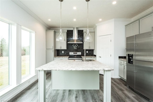 kitchen with stainless steel appliances, a healthy amount of sunlight, a sink, and wall chimney range hood