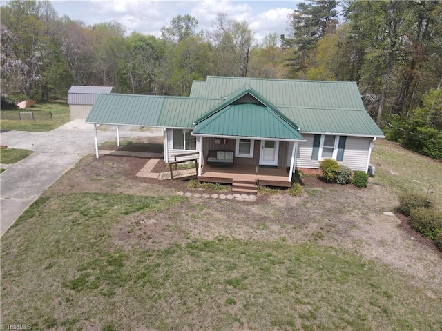 rear view of property featuring a yard, a porch, a carport, metal roof, and concrete driveway