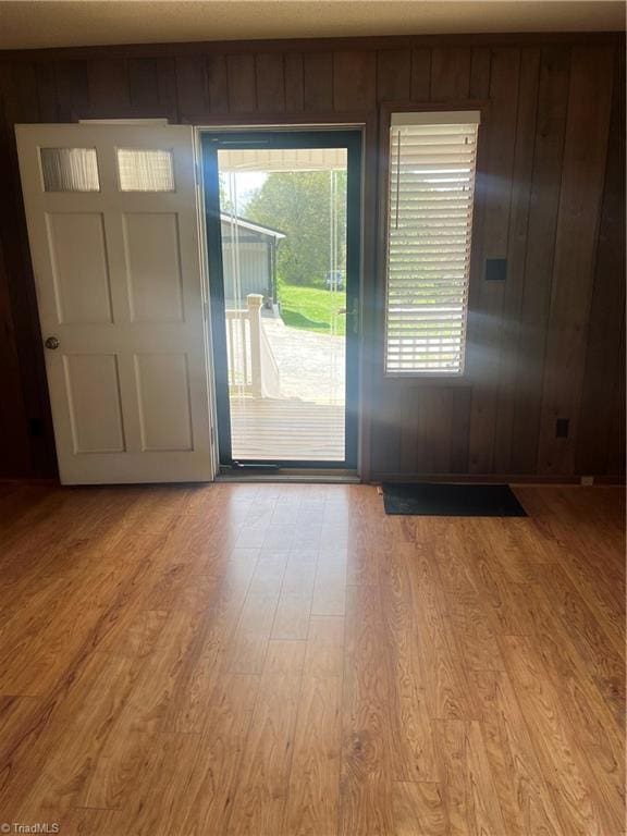 entryway featuring light wood-style floors, wood walls, and a wealth of natural light