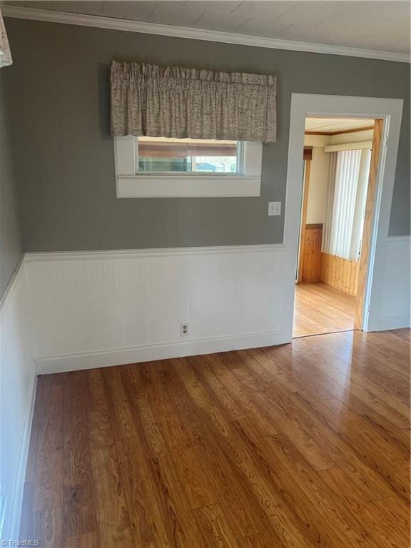 unfurnished room featuring wainscoting, crown molding, and wood finished floors