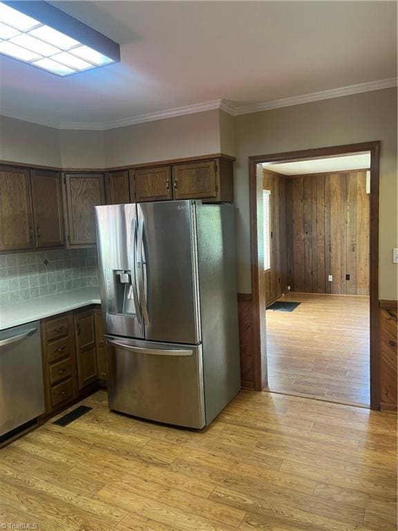 kitchen featuring tasteful backsplash, light wood-type flooring, ornamental molding, visible vents, and stainless steel appliances