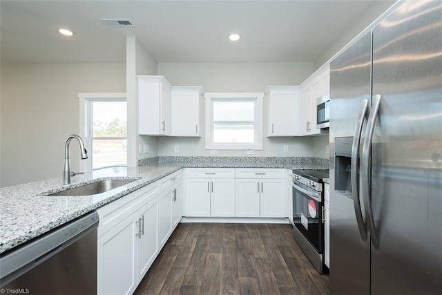 kitchen featuring dark wood-type flooring, sink, light stone counters, stainless steel appliances, and white cabinets