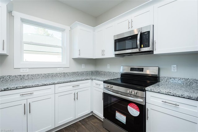 kitchen with stainless steel appliances, dark hardwood / wood-style floors, light stone countertops, and white cabinets