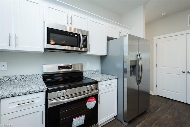 kitchen featuring white cabinetry, stainless steel appliances, light stone countertops, and dark wood-type flooring