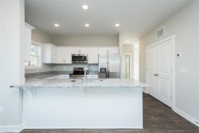 kitchen featuring sink, appliances with stainless steel finishes, a kitchen breakfast bar, white cabinets, and kitchen peninsula