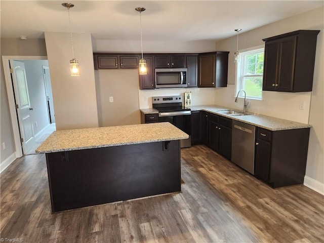 kitchen with appliances with stainless steel finishes, a kitchen island, and dark wood-type flooring