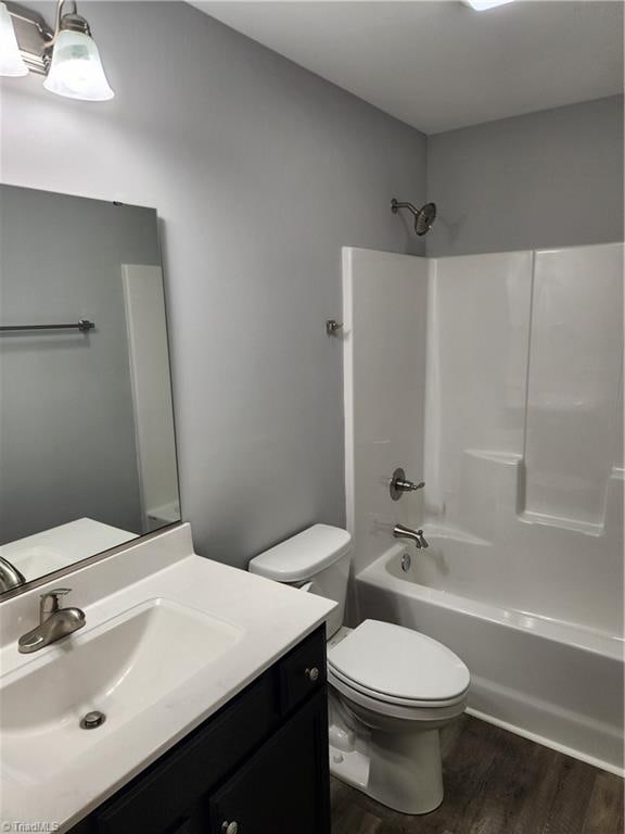 full bathroom featuring  shower combination, vanity, hardwood / wood-style floors, and toilet