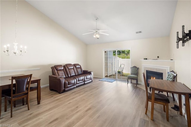 3972 Creekside Ct, Winston-Salem, NC 27127 - living area with vaulted ceiling, a tiled fireplace, a ceiling fan, a chandelier, and light wood-style floors