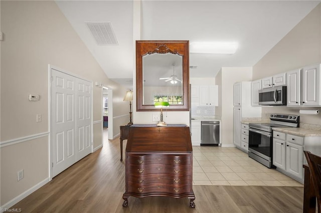 3972 Creekside Ct, Winston-Salem, NC 27127 - kitchen with appliances with stainless steel finishes, light countertops, white cabinets, a ceiling fan, and light wood finished floors