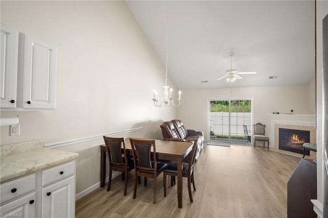 3972 Creekside Ct, Winston-Salem, NC 27127 - dining area featuring light wood-style flooring, a ceiling fan, a fireplace with flush hearth, a chandelier, and high vaulted ceiling