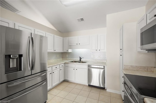 3972 Creekside Ct, Winston-Salem, NC 27127 - kitchen featuring appliances with stainless steel finishes, vaulted ceiling, white cabinets, decorative backsplash, and a sink