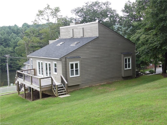 rear view of house featuring a deck and a lawn