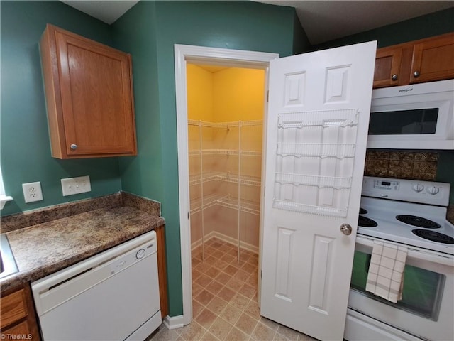 10 Dunlevy Way, Greensboro, NC 27455 - kitchen featuring white appliances, brown cabinets, and dark countertops