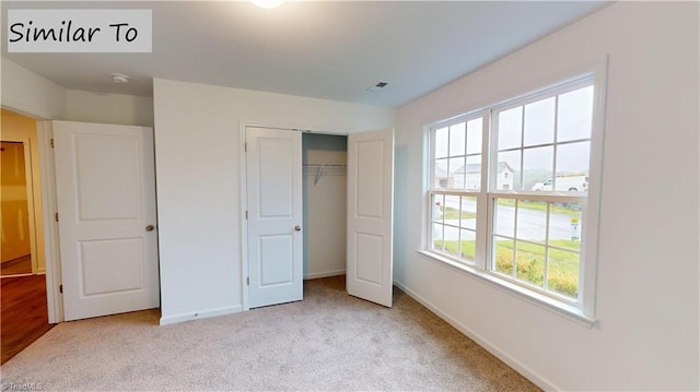 unfurnished bedroom featuring light colored carpet and a closet