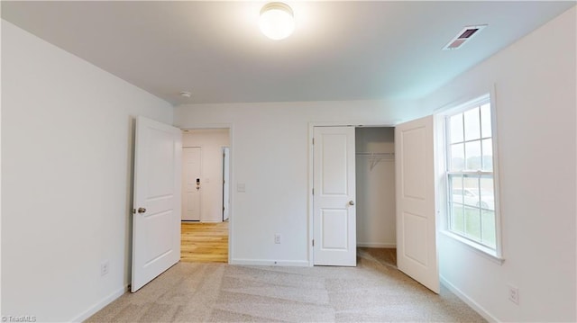 unfurnished bedroom with light colored carpet and a closet