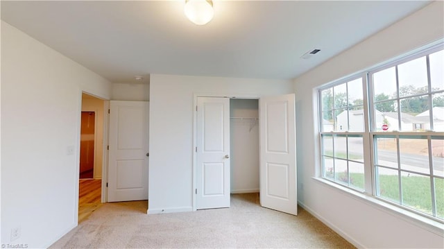 unfurnished bedroom featuring light colored carpet and a closet