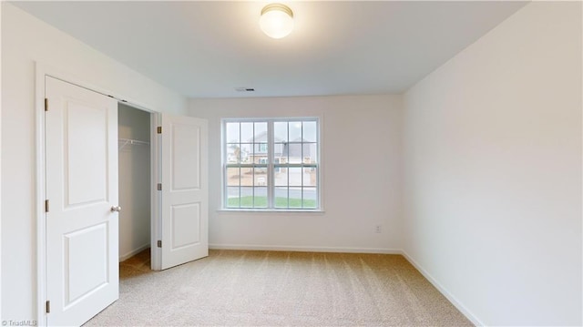 unfurnished bedroom featuring light carpet and a closet