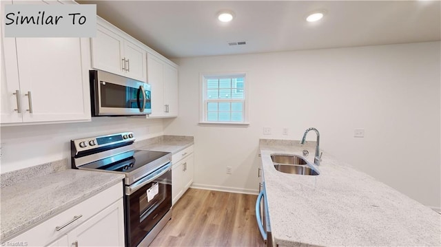 kitchen with appliances with stainless steel finishes, light stone counters, sink, light hardwood / wood-style flooring, and white cabinets