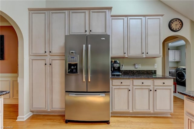 kitchen featuring stainless steel refrigerator with ice dispenser, arched walkways, washer / clothes dryer, and light wood-type flooring