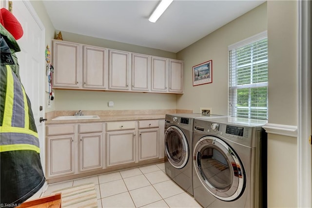laundry room featuring a sink, light tile patterned floors, washing machine and dryer, and cabinet space