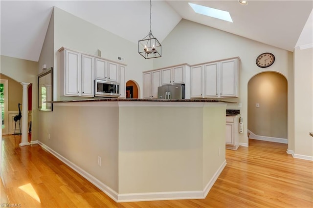 kitchen featuring a skylight, arched walkways, and stainless steel appliances