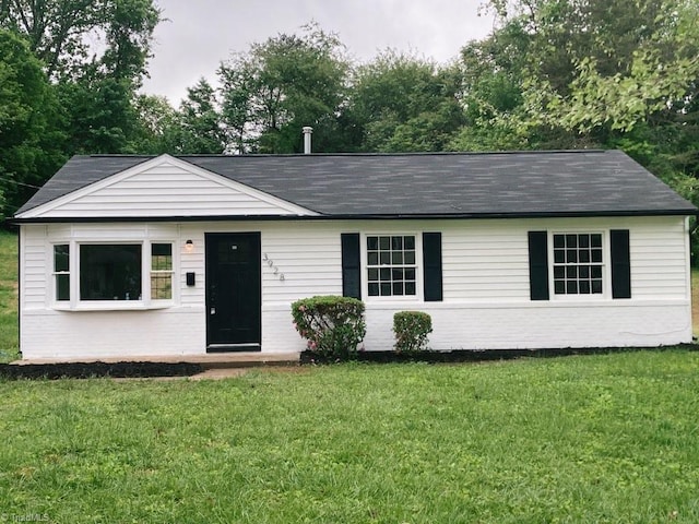 ranch-style home with brick siding, roof with shingles, and a front yard