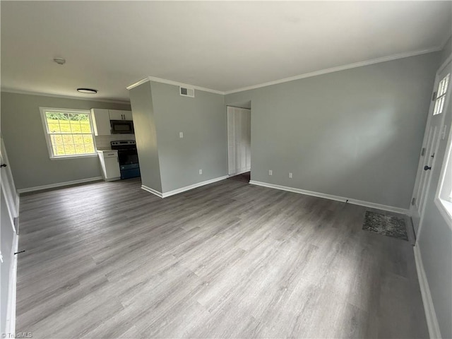 interior space featuring crown molding, baseboards, wood finished floors, and visible vents