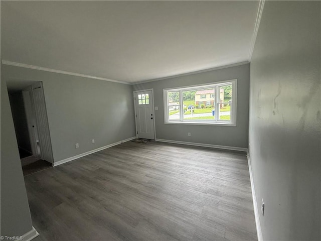 unfurnished living room featuring baseboards, ornamental molding, and wood finished floors